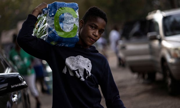 A volunteer carries bottles of water at a distribution site in Jackson, Mississippi.