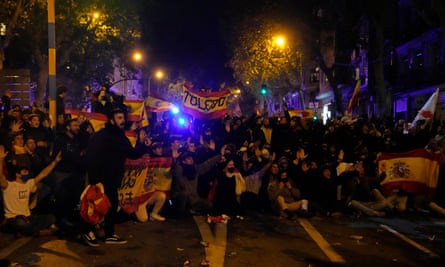 Demonstrators sit in the street under banners and red and yellow flags