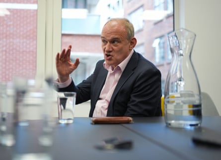Lib Dems leader Ed Davey, dressed in pink shirt and dark suit, gesticulates in mid-conversation