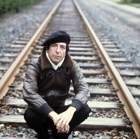 Leonard Cohen in a black beret, sitting on railway tracks