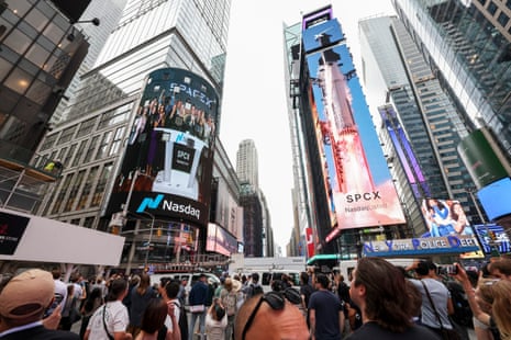 SpaceX employees are shown on a screen celebrating the company’s debut on the Nasdaq market in New York.
