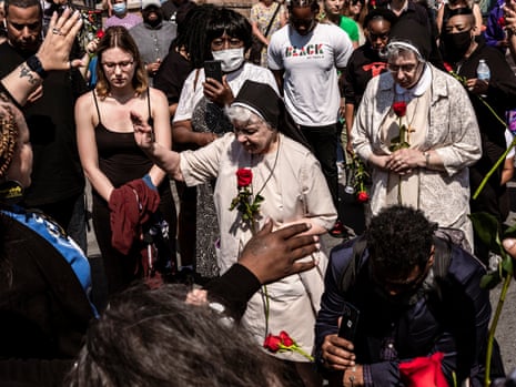 Nuns, surrounded by many people, hold roses.