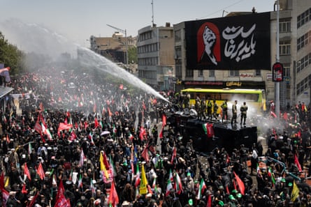 Water is sprayed over a crowd during the funeral procession for Ali Khamenei in Tehran.