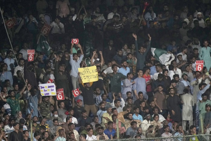 Spectators, some holding placards, cheer for the teams.