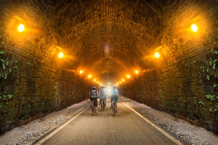 Cyclists riding through lit tunnel