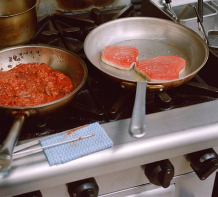 A pan of tomatoes and a pan of tuna on a stove