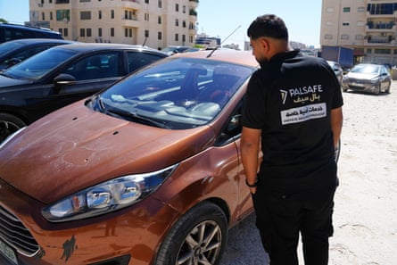 A man looks at a car with a bullet hole through the windscreen