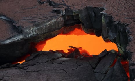 A crack in the surface of solidified lava in Hawaii shows hot glowing magma in an underground tube beneath