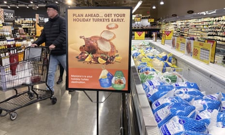 A man shops at a grocery store behind a sign encouraging shoppers to buy turkeys early