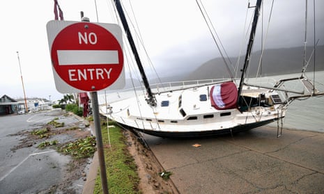 A damaged building can be seen behind a boat that was pushed on to a bank in Airlie Beach by Cyclone Debbie