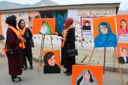 Attendees stand next to portraits of women who suffered violence at an exhibition in Faizabad, Badakhshan province in December 2019