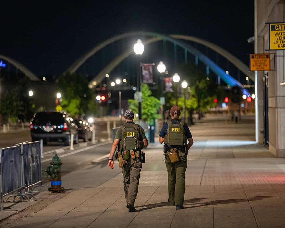 Two FBI agents walking away from the camera along a pavement