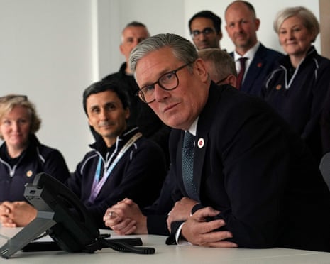 Keir Starmer listening to a black phone, while dressed in a black suit
