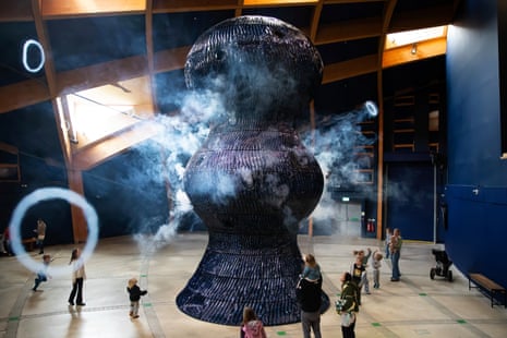 People look at a tall structure blowing large smoke rings over their heads