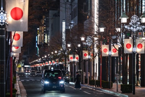 A woman crosses a quiet street in the usually busy streets of Ginza just hours before the start of 2024.