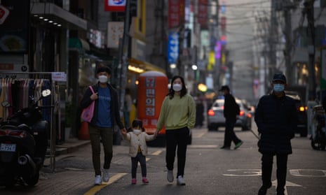 Pedestrians wearing face masks make their way along a street in Seoul on November 16, 2020. (Photo by Ed JONES / AFP)