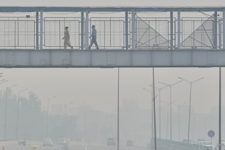 People cross an overhead bridge amid the smog