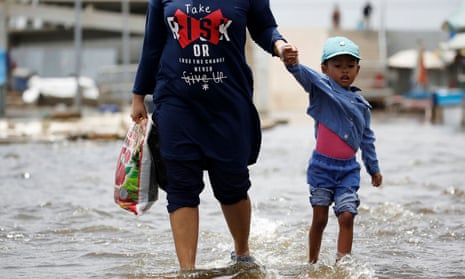 A young girl and a woman walk through water at Kali Adem port, north of Jakarta in Indonesia