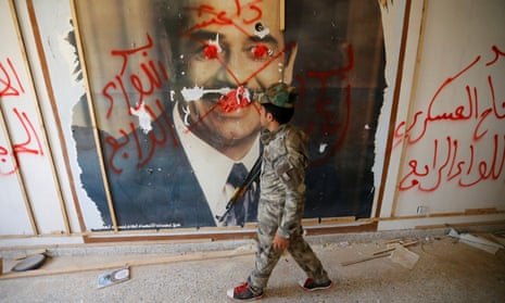 A fighter from the Iraqi Shia Badr Organisation looks at a poster depicting images of Saddam Hussein on the outskirts of Falluja. REUTERS/Thaier Al-Sudani 
