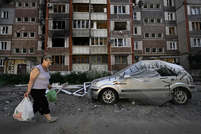 A woman gathers her belongings from a heavily damaged residential building in Saltivka, a northern district of Kharkiv.