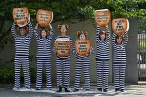People dressed in stripy black and white pajamas and fake monkey ears hold up signs shaped like coconuts