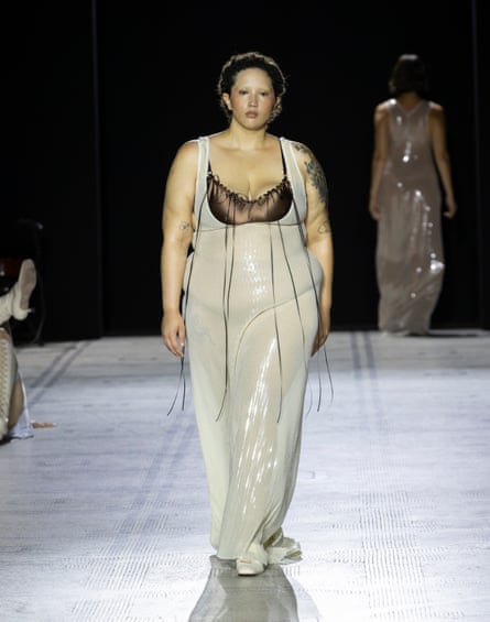 Model wearing white sheer dress with black bodice on catwalk