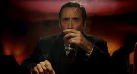 Nicolas Cage sitting down and wearing a dark suit while drinking wine and smoking in Spider-Noir