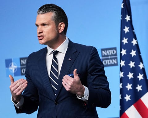 Pete Hegseth delivers a statement beside an American flag