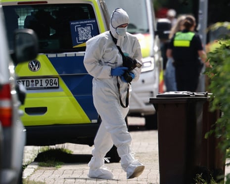 A forensic police officer with a camera works near the scene where five people were killed in a shooting in Stade, northern Germany.