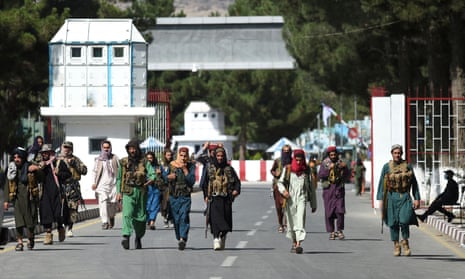 Taliban fighters walk in at the main entrance gate of Kabul airport on Saturday.