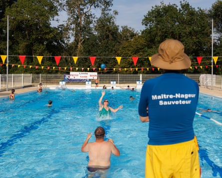 Lifeguard/swimming instructor stood watching as people swim in the pool