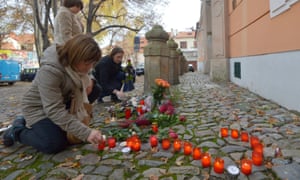 A woman forms a question mark using candles in front of the French embassy in Prague.