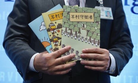 A police official displays three children's books that portray Hongkongers during the 2019 unrest as sheep defending their village from wolves
