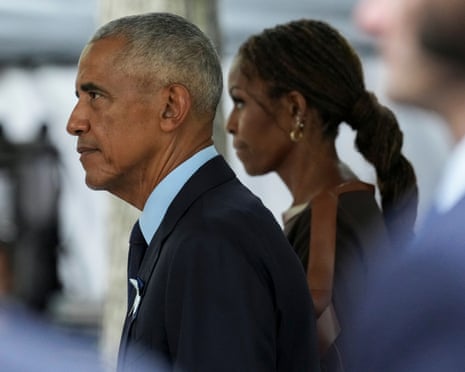 Barack and Michelle Obama walk in profile, arriving at a memorial event