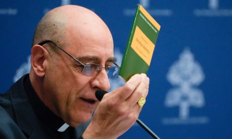 The cardinal holds up the 20-page document with a green cover