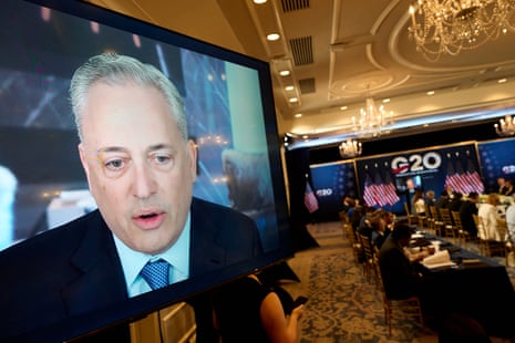 An older man on a video screen at a conference.