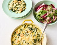 A yellow dish holds Jamie Oliver's creamy fish pie pasta bake with spinach, beside a salad and plates