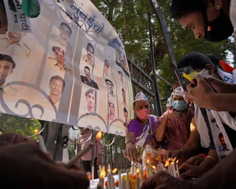 people light candles at a memorial showing photos of deceased people