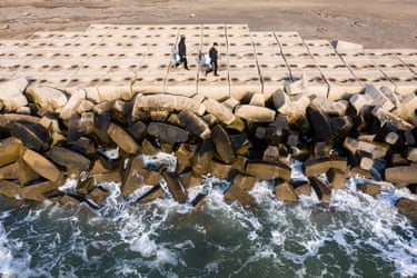 Fishermen walk along a sea wall in Tianjin