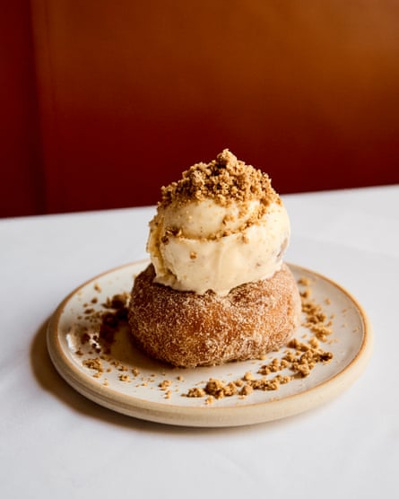 Plated doughnut topped with a scoop of icecream sprinkled with crumble mixture