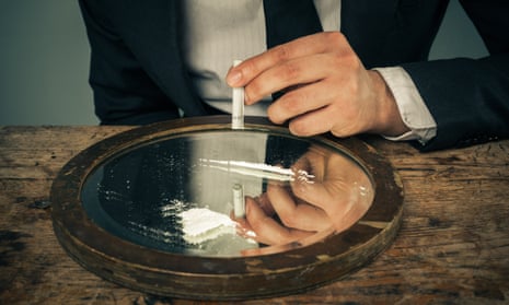 A person in a suit prepares a line of cocaine on a mirror.