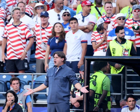Coach Mauricio Pochettino gestures and shouts on the sideline, fans in striped jerseys behind him