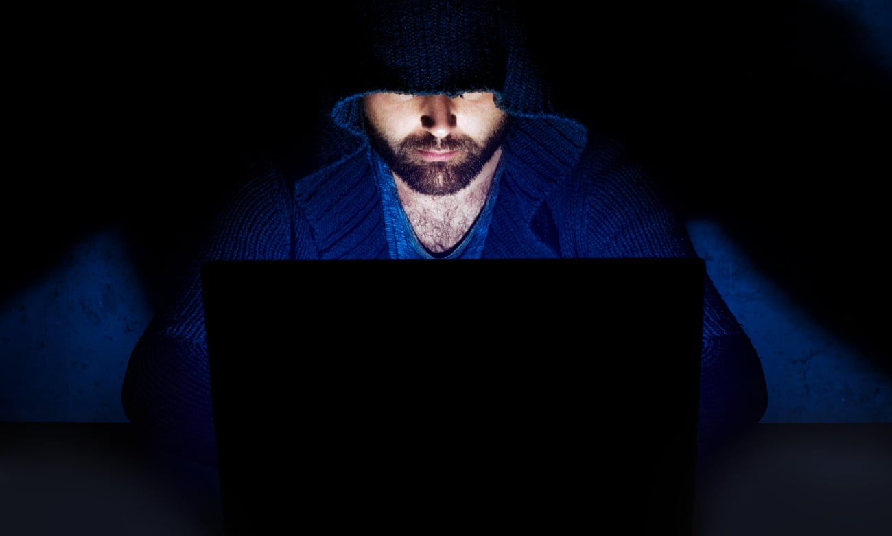 A man in a hoodie at a computer