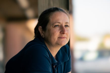 A woman in a blue collared shirt looks hopeful as she stares into the distance