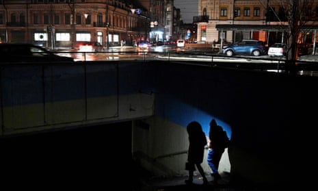 People use a torch as they enter an underground passage during a blackout after Russian strikes in Kyiv.