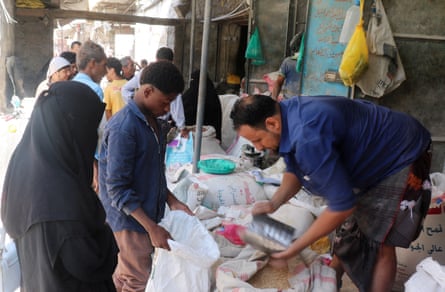 A seller pours grain into a sack at a market