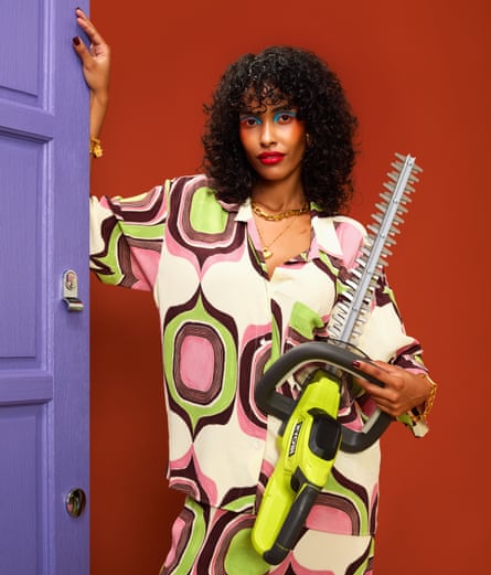 Women in bright patterned clothes, opening a purple door, holding a hedge trimmer