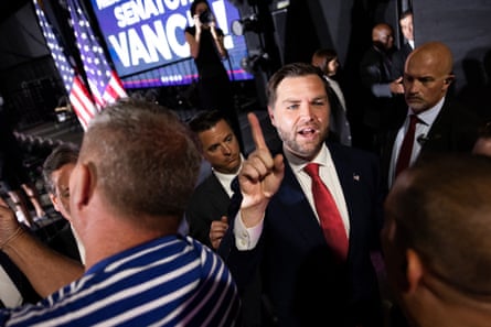 vance walks among group of men whiel raising one finger