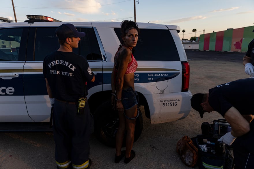 A paramedic attends to a woman in red