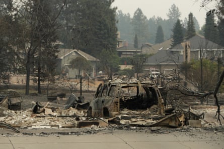 burnt car and rubble outside homes
